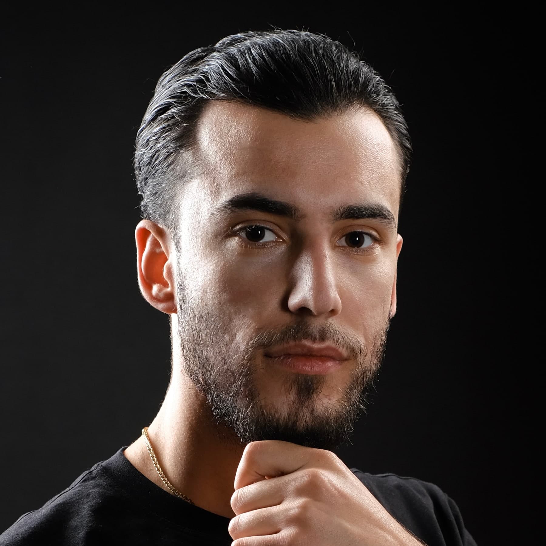 Close-up portrait of Orgito Baraj, lit against a black background